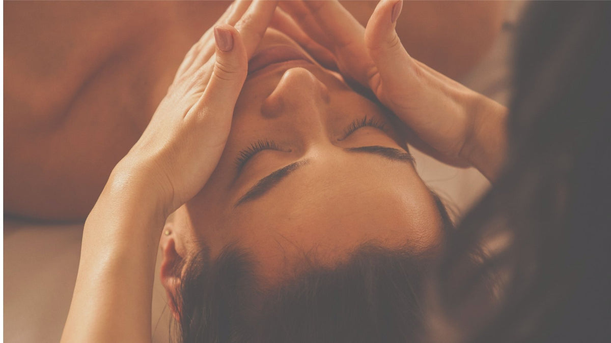 Close-up of a person receiving a head massage with hands on a blurred background